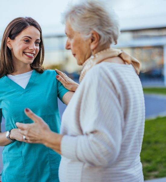 Caring Nurse Interacting with Elderly Woman Outdoors Caring Nurse Interacting with Elderly Woman Outdoors