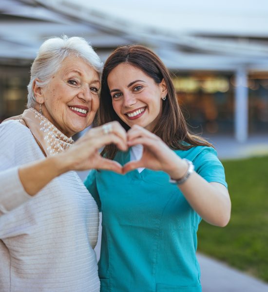 Senior Woman and Caregiver Forming Heart Shape Outdoors Senior Woman and Caregiver Forming Heart Shape Outdoors